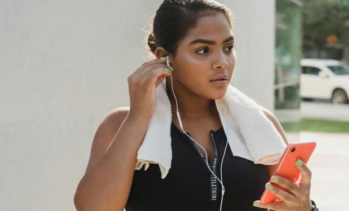 Μια γυναίκα που κρατά το τηλέφωνό της φορώντας ακουστικά