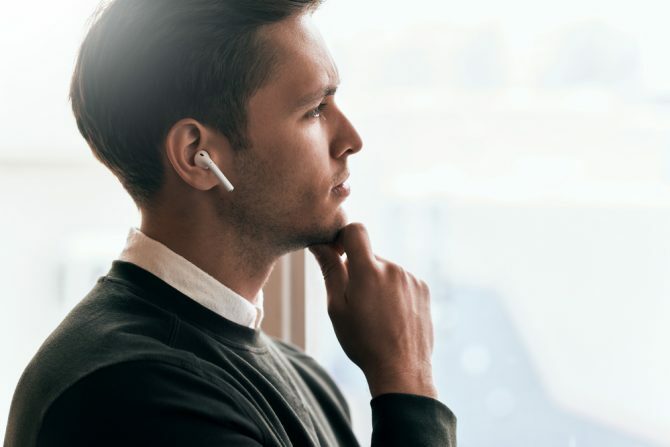 Ο άνθρωπος σκέφτεται ενώ κοιτάζει έξω από το παράθυρο φορώντας ασύρματα ακουστικά αυτιού